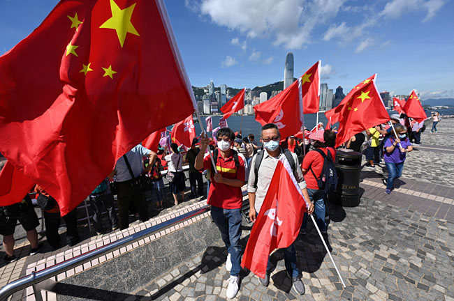 홍콩 반환 25주년을 앞둔 28일 홍콩 빅토리아항에서 시민들이 중국 오성홍기와 홍콩 국기를 들고 있다. 영국 식민지였던 홍콩은 지난 1997년 7월 1일 중국에 반환됐다. 연합뉴스·AFP