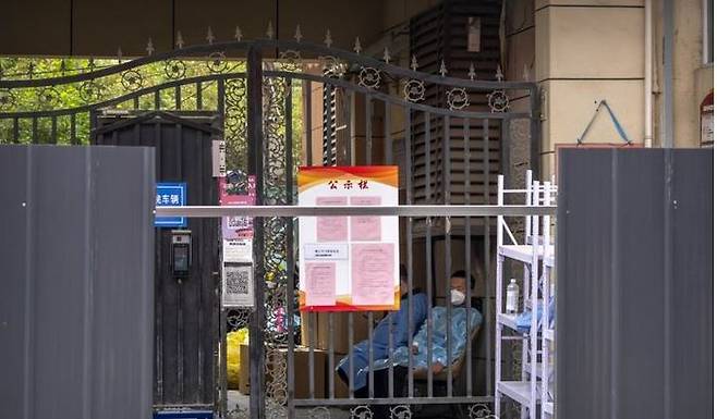 중국 베이징시 차오양구의 한 클럽과 관련한 코로나19 집단 감염이 빠르게 확산한 지난달 14일 봉쇄조치로 철제 바리케이드가 설치된 베이징의 한 주거건물 입구에서 남성들이 무료하게 앉아 있다.ⓒ 베이징 AP 연합뉴스