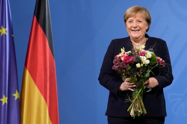 지난해 12월 메르켈 전 독일 총리가 베를린 총리실에서 16년의 임기를 마치고 올라프 숄츠 총리에게서 꽃다발을 건네받고 활짝 웃고 있다. 연합뉴스