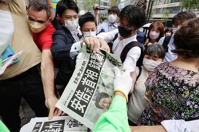 (도쿄 AFP=뉴스1) 최종일 기자 = 8일 오후 일본 도쿄 도심에서 아베 신조 전 총리의 피습 소식을 전하는 호외를 받아 보기 위해 시민들이 몰려들고 있다.   (C) AFP=뉴스1