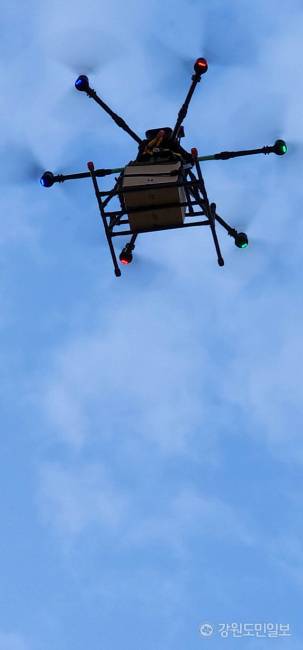 ▲ ▲지난 3일 망상해수욕장 북쪽 끝자락에 위치한 망상오토캠핑리조트 앞 해변 데크에 마련된 ‘드론배송존’애서 디스이즈엔지니어링이 운용하는 ‘드론음식배송서비스’에 한 가족으로부터 치킨 주문을 받은 드론이 배달을 위해 치킨을 싣고 망상상가 뒷편 공터에서 출발, 망상해안가 70m 상공을으로 날아올라 1.5km 구간을 비행하고 있다.