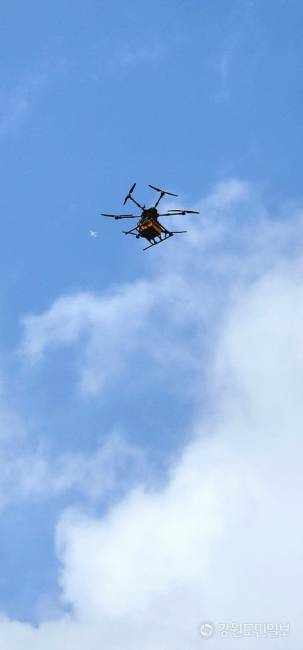 ▲ 지난 3일 망상해수욕장 북쪽 끝자락에 위치한 망상오토캠핑리조트 앞 해변 데크에 마련된 ‘드론배송존’애서 디스이즈엔지니어링의 ‘드론음식배송서비스’가 운영되고 있는 가운데, 한 가족으로부터 치킨 주문을 받은 드론이 배달을 위해 치킨을 싣고 망상상가 뒷편 공터에서 출발, 망상해안가 70m 상공을으로 날아올라 망상오토캠핑리조트까지 1.5km 구간을 비행하고 있다.