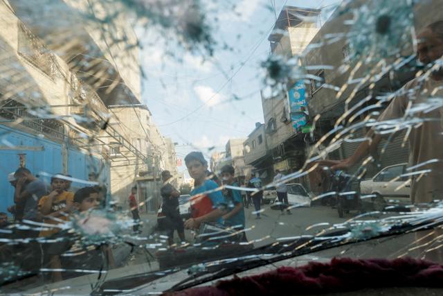 7일 이스라엘 공격으로 파괴된 차량 밖으로 팔레스타인 가자지구 시가지와 어린이들이 보인다. 가자지구=로이터 연합뉴스