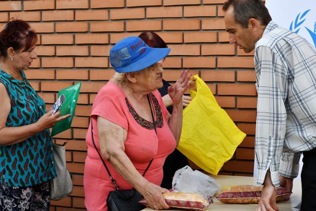 지난 4일 우크라이나 자포리자의 인도적 구호 물품 배급소에서 주민들이 빵을 받고 있다. 자포리자=AP 뉴시스