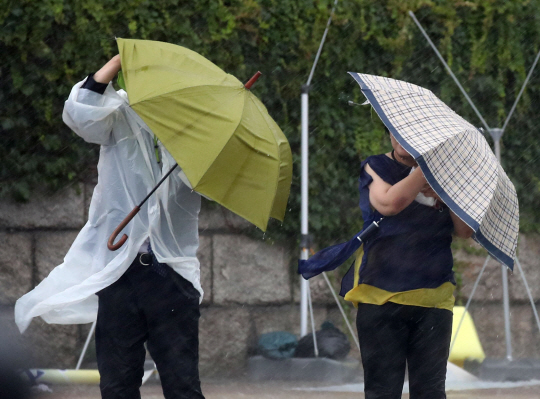 서울 등 중부를 중심으로 폭우가 쏟아지는 8일 오후 서울 여의도 국회 정문 앞에서 시민들이 강한 바람에 우산을 기울여 쓰고 지나가고 있다. 뉴시스