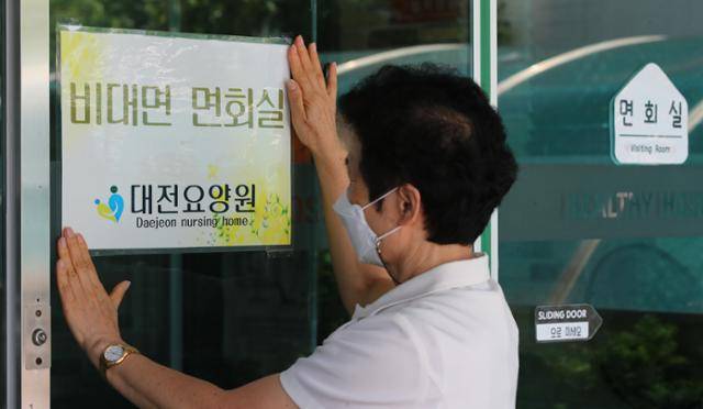 방역당국이 요양병원·시설 접촉 면회를 금지하고 병상확보 행정명령을 발동하는 등 코로나19 6차 대유행에 대비한 방역대책을 발표한 지난달 20일 오후 대전 서구 대전요양원에서 직원이 비접촉면회실 안내 문구를 붙이고 있다. 뉴스1
