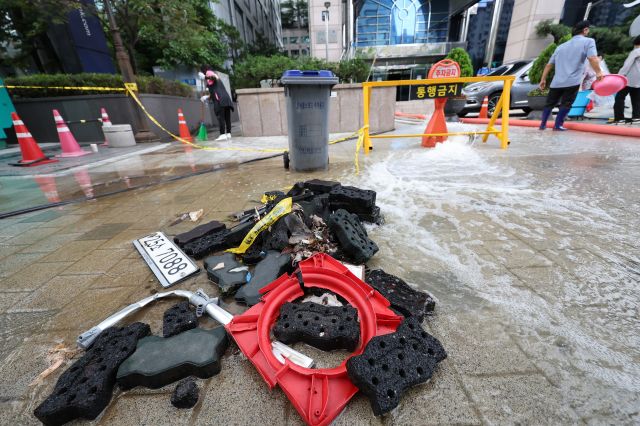 10일 오전 비가 소강상태를 보이는 가운데 서울 강남역 인근 한 빌딩에서 배수 작업 도중 관계자들이 쓰레기를 치우고 있다. 연합뉴스