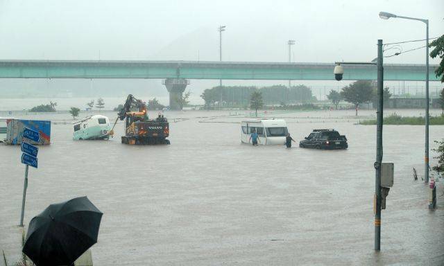 중부지역에 200㎜가 넘는 집중폭우가 쏟아진 9일 오전 강원 원주시 문막교 인근 섬감이 범람해 고수부지에 주차된 카라반 차량을 빼내고 있다. 연합뉴스