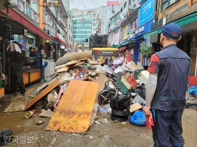 11일 오전 폭우 피해가 발생한 서울 동작구 남성사계시장에서 한 복구 인력이 시장 길목에 쌓인 쓰레기를 망연자실한 표정으로 바라보고 있다. 김재현 기자