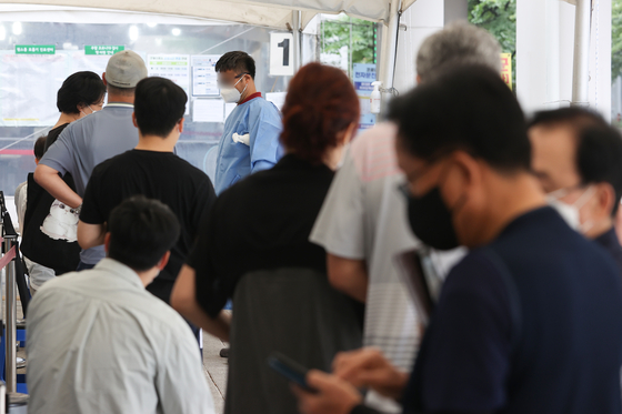 People wait in line to get tested for Covid-19 at a testing center in Mapo District, western Seoul, Thursday. [YONHAP]