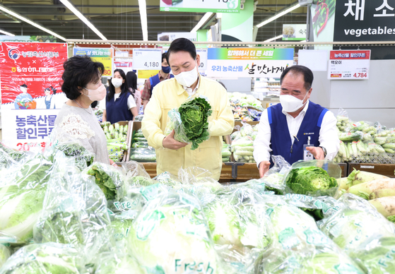President Yoon Suk-yeol speaks with a customer at the fresh produce section of Hanaro Mart in Yangje on Thursday. [YONHAP]
