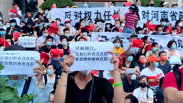 지난달 10일 중국 정저우 인민은행 앞에서 시민들이 예금 인출 동결 해제를 요구하는 플래카드를 들고 시위하는 모습. 로이터연합뉴스