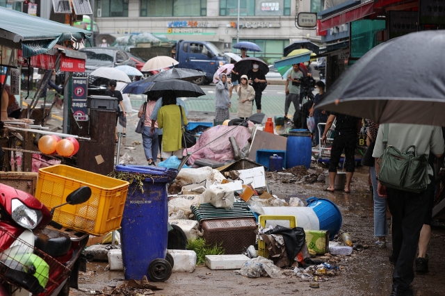 9일 서울 동작구 남성사계시장 상인들이 폭우로 침수피해를 입은 상점을 살펴보고 있다. 연합뉴스