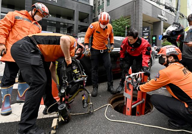 소방관계자들이 11일 서울 서초동 주변 도로에서 사흘 전 내린 폭우 당시 맨홀에 빠진 실종자를 찾기 위한 수색작업을 하고 있다. 서재훈 기자