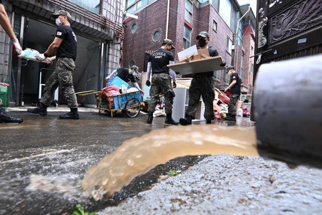 수도권 등 중부지방에 내린 폭우로 피해가 속출하고 있는 11일 오후 경기 군포시 산본동 저지대 주택가에서 육군 제51보병사단 예비군지휘관과 상근 예비역들이 복구작업 지원에 나서 침수가구 집기류 등 폐기물을 처리하고 있다. 뉴시스