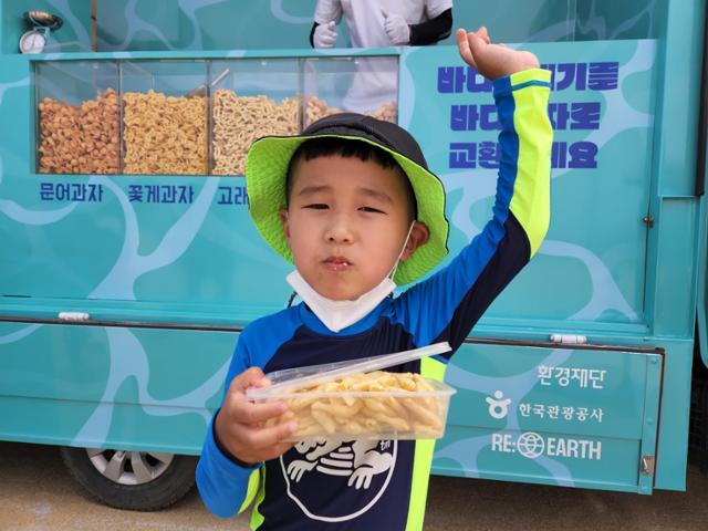 14일 강원도 속초해수욕장에서 열린 씨낵 캠페인에 참여한 김대호(6) 어린이가 쓰레기와 교환한 과자를 다회용 용기에 담아 먹고 있다. 속초=박소영 기자