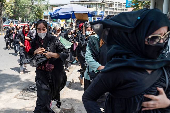 아프가니스탄 수도 카불에서 13일(현지시간) 여성인권을 요구하며 시위를 벌이던 여성들이 탈레반 대원들의 경고 사격에 황급히 몸을 피하고 있다. 카불 | AFP연합뉴스