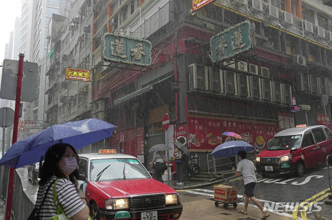 [홍콩=AP/뉴시스] 태풍이 접근하면서 비가 내리는 홍콩 시내에서 9일 코로나19 예방을 위해 마스크를 착용한 시민들이 바쁘게 길을 가고 있다. 2022.08.10