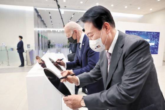 윤석열 대통령과 조 바이든 미국 대통령이 지난 5월 20일 경기 평택 삼성전자 반도체 공장에서 만나 웨이퍼에 서명하고 있다. 뉴스1