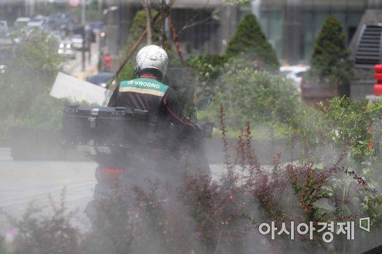 서울 중구 명동 중앙우체국 앞 물안개 분수에서 배달원이 분주하게 이동하고 있다. /문호남 기자 munonam@