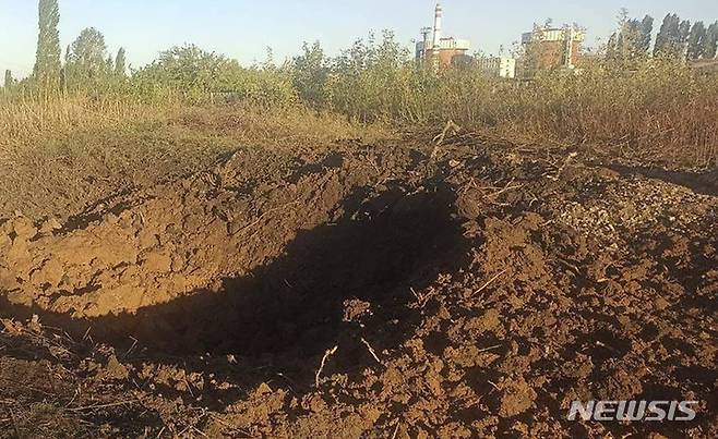 In this photo provided by the South Ukraine nuclear power plant, a crater left by a Russian rocket is seen 300 meter from the South Ukraine nuclear power plant, in the background, close to Yuzhnoukrainsk, Mykolayiv region, Ukraine, Monday, Sept. 19, 2022. (South Ukraine Nuclear Power Plant Press Office via AP)