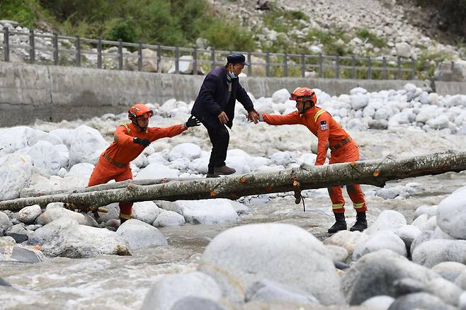 지난 6일(현지시각) 중국 쓰촨성 간쯔장족자치구 루딩현에서 구조대원들이 간이 다리 위를 지나는 주민들의 피난을 돕고 있다. 루딩현에서는 지난 5일 규모 6.8 강진이 발생했다. /AFP 연합뉴스