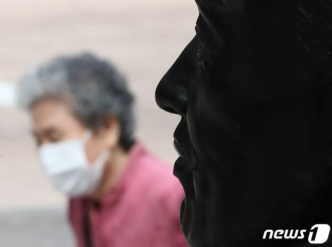 실외 마스크 착용 의무 전면 해제를 하루 앞둔 25일 서울 명동거리에서 흉상 앞으로 마스크 쓴 시민이 지나가고 있다. 2022.9.25/뉴스1 ⓒ News1 이성철 기자