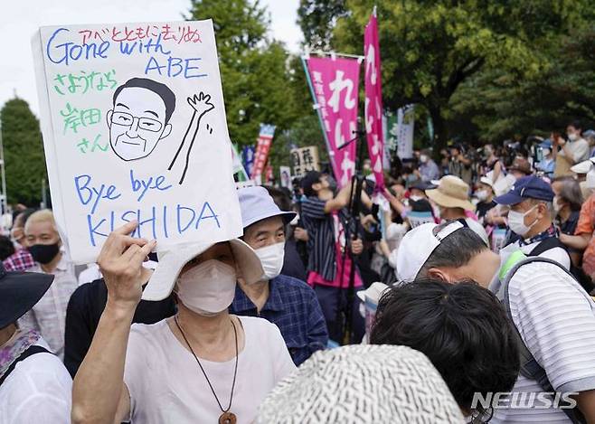 [도쿄=AP/뉴시스] 27일 일본 도쿄에서 아베 신조 전 총리의 국장에 반대하는 시위가 열려 한 참가자가 기시다 후미오 총리를 비난하는 손팻말을 들고 있다. 2022.09.27.