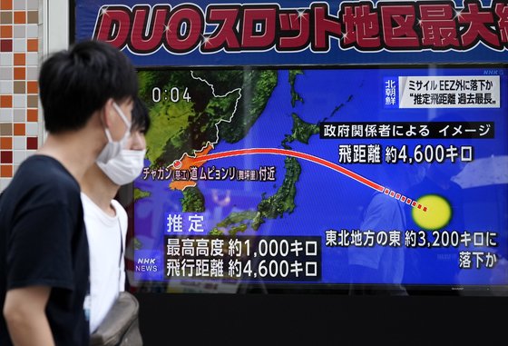 4일 일본 도쿄에서 마스크를 쓴 시민들이 북한의 미사일 발사 소식을 알리는 전광판 앞을 지나고 있다. EPA=연합뉴스