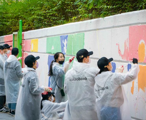 카카오뱅크 임직원들이 지난 20일 성남시 중원구 은행중학교에서 '모두의 벽화 그리기' 봉사활동에 참여해 벽화를 채색하고 있다. 카카오뱅크 제공