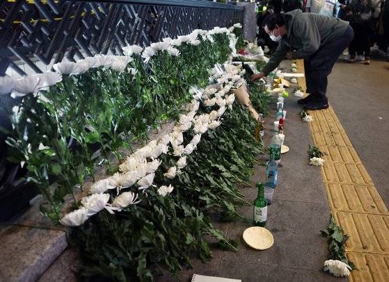 30일 저녁 서울 용산구 이태원 참사 사고 인근에 마련된 추모공간에서 한 시민이 조화를 내려놓고 있다. 뉴스1