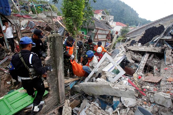22일(현지 시각) 구조대원들이 무너진 건물 잔해 사이로 희생자의 시신을 옮기고 있다./로이터 연합뉴스