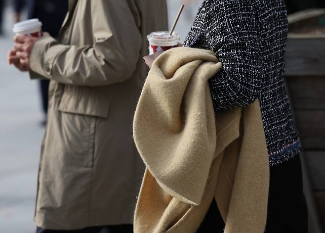 큰 추위 없는 늦가을 날씨가 이어지고 있는 지난 21일 오후 겉옷을 손에 든 시민들이 광화문네거리를 지나고 있다.    연합뉴스