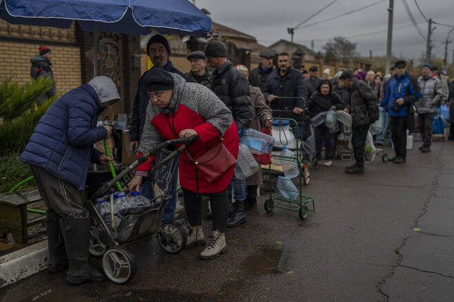 지난 20일 우크라이나가 탈환한 헤르손 지역에서 식수를 공급받기 위해 주민들이 줄을 서 있다. AP 연합뉴스
