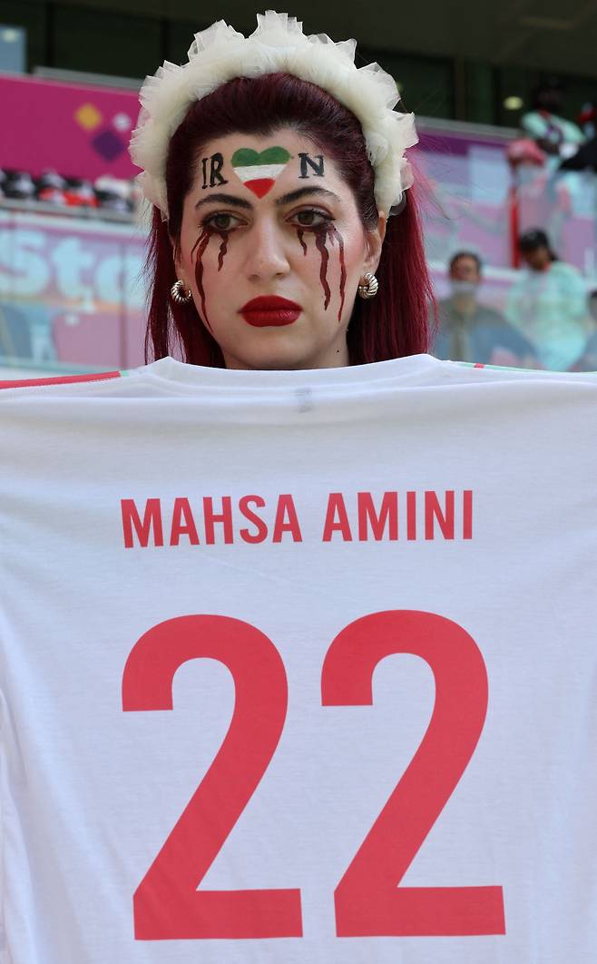 한 이란 여성이 마흐사 아미니의 이름이 적힌 옷을 들고 있다./AFP연합뉴스