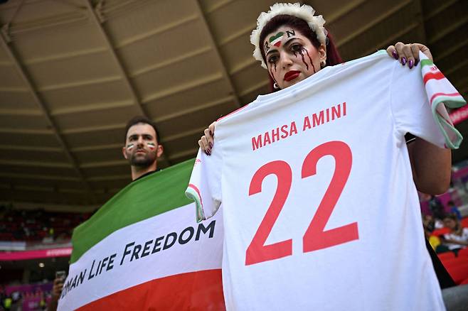 25일(현지 시각) 이란과 웨일스의 B조 경기에서 이란 축구 팬이 마흐사 아미니의 이름이 적힌 티셔츠를 들고 포즈를 취했다. /로이터연합뉴스