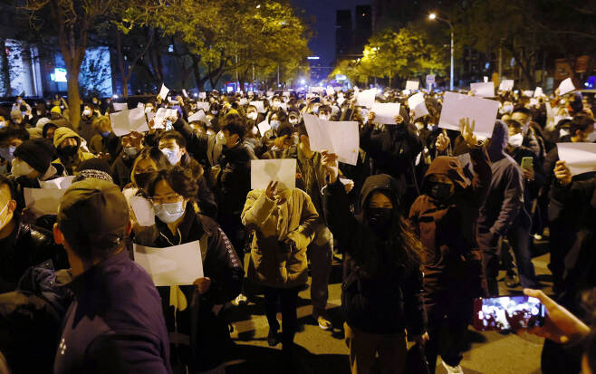 27일(현지시간) 중국 베이징에서 신장 우루무치 아파트 화재 사고 희생자를 추모하기 위해 모인 시민들이 백지를 들며 정부의 봉쇄에 항의를 표시하고 있다. [EPA]