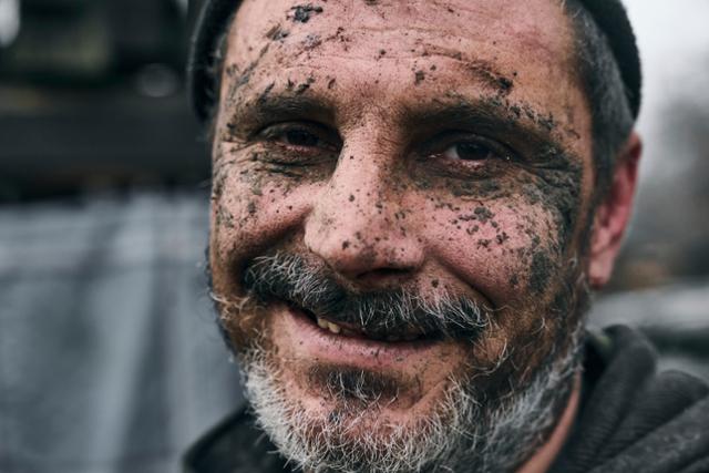 지난달 22일 우크라이나 동부 도네츠크 지역의 최전선에서 얼굴에 진흙을 뒤집어쓴 우크라이나 병사가 카메라를 향해 미소짓고 있다. AP=연합뉴스