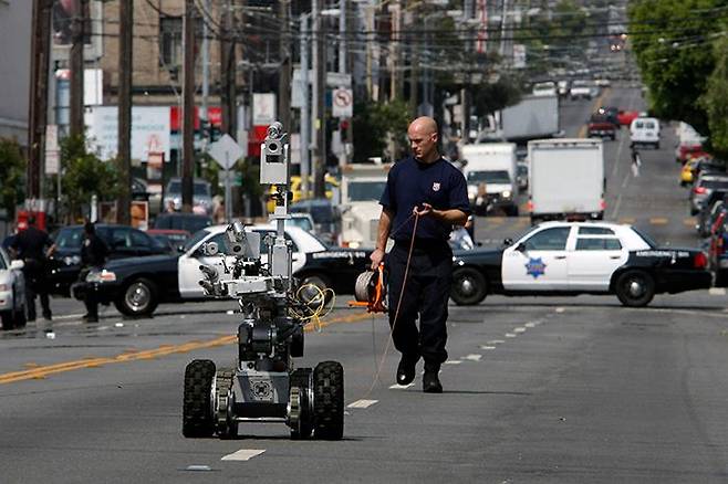 샌프란시스코 경찰의 ‘살상 로봇’ - 미 캘리포니아주 샌프란시스코 시내에서 한 경찰관이 로봇으로 폭발물을 탐지하고 있다. 현지 경찰국은 극한 범죄 상황에서 ‘폭탄을 장착한 살상 로봇’을 운용하겠다는 계획을 최근 시 감독위원회로부터 승인받았다. /AP 연합뉴스