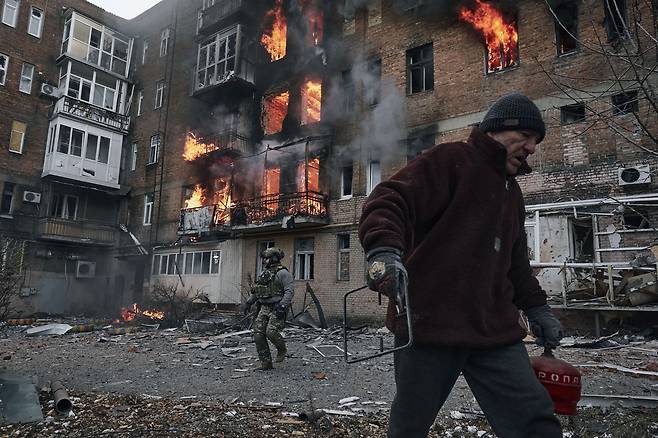 7일(현지시간) 우크라이나 동부 도네츠크 바흐무트 시내 한 아파트에 러시아군 포격으로 화재가 발생했다. 해당 아파트의 한 주민이 대피하고 있다. / 사진=AP 연합뉴스