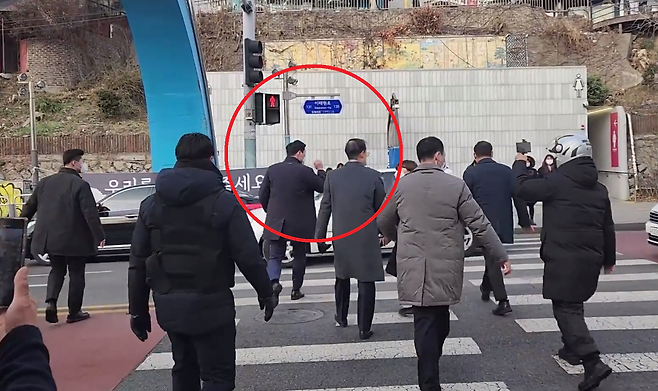 한덕수 국무총리가 지난 19일 이태원 참사 희생자 합동분향소를 찾았다가 유족들 항의로 자리를 뜨며 빨간 신호등이 켜져 있는 도로를 건너는 모습. 시사IN 영상 갈무리