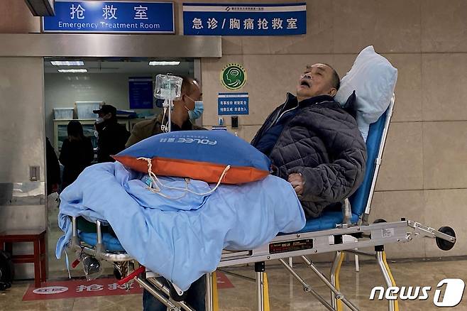 22일(현지시간) 코로나19 확산 속 중국 충칭의 병원 응급실 입구에 노인 확진자가 들것에 누워 대기를 하고 있다. ⓒ AFP=뉴스1 ⓒ News1 우동명 기자