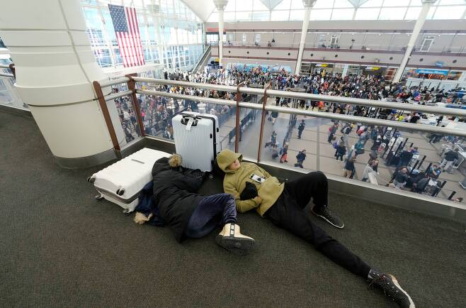23일 미국 덴버 국제공항 터미널 한 켠에서 여행객들이 바닥에 누워 자고 있다. 갑자기 몰아친 겨울 눈폭풍으로 항공기가 무더기 결항 됐다./AP 연합뉴스