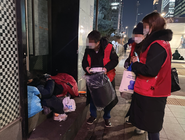 브릿지센터 상담원들이 8일 오후 8시 30분쯤 서울 종각역 앞에서 노숙인 아웃리치를 진행하고 있다. 노숙인들은 대개 침낭 밖으로 팔만 뻗어 동절기 키트를 받고는 다시 잠에 들었다. 최은서 기자