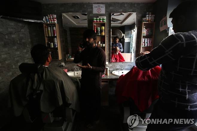 파키스탄 대규모 정전…불꺼진 이발소 (EPA=연합뉴스) 23일(현지시간) 파키스탄에서 대규모 정전이 발생한 가운데 페슈와르의 한 이발소에서 이발사가 불이 꺼진 매장에서 손님의 머리를 깎고 있다. 재판매 및 DB금지.