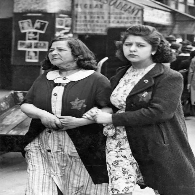 1942년 6월 독일이 점령한 파리에서 노란색 배지를 착용한 여성들이 불안한 표정으로 거리를 걷고 있다.