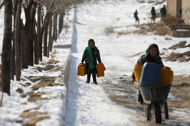 2023년 1월 26일(현지시간)아프가니스탄 카불의 눈 덮인 거리에서 한 아프간 소녀가 빈 물통을 나르고 있다. 로이터 연합뉴스