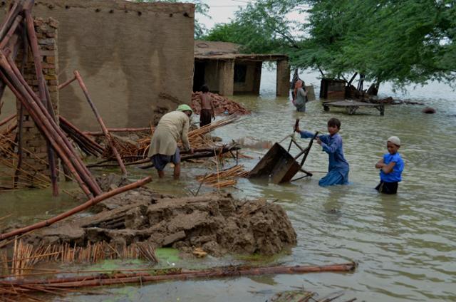 지난해 8월 25일 파키스탄 남서부 발루치스탄주 자파라바드에서 한 가족이 홍수로 침수된 집에서 가재도구를 건져내고 있다. 자파라바드=AP 연합뉴스