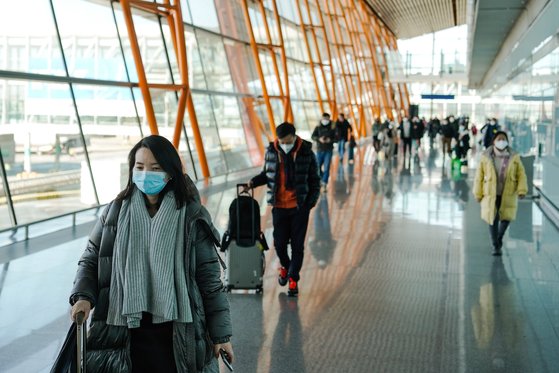 지난 28일 중국 베이징 서우두 공항에 마스크를 쓴 승객들이 수하물을 들고 입국하고 있다. EPA