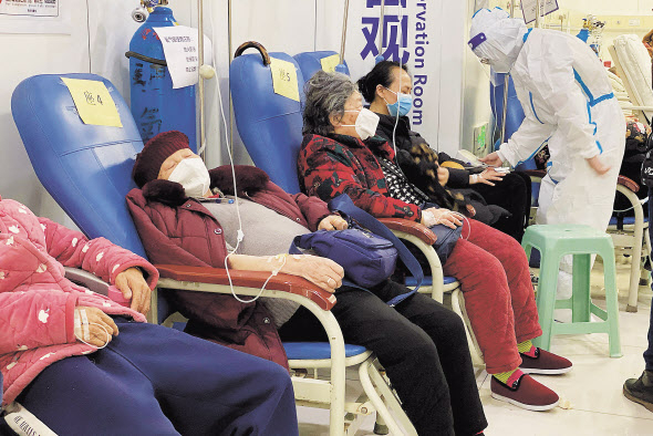 지난해 말 중국 남서부 충칭시 충칭의과대학 제2부속병원에서 코로나19 환자들이 팔에 주사를 꽂은 채 줄지어 앉아있다. [연합]